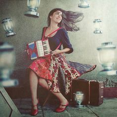 a woman is sitting on the steps with an accordion and music box in her hand