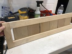 a person holding a piece of wood in front of a bench with tools on it