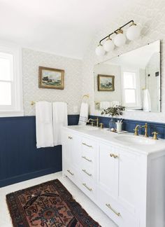 a bathroom with blue and white walls, gold trimmings and an area rug on the floor