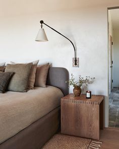 a bed room with a neatly made bed and a lamp on the wall next to it