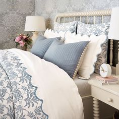 a bed with blue and white comforters in a bedroom next to a night stand