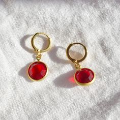 These earrings feature 10mm siam ruby red vintage stones attached to gold plated 11mm hoops. Red 14k Gold Pierced Earrings, Red Faceted Dangle Earrings, Gold Ruby Round Earrings, Red Faceted Drop Earrings, Classic Red Ruby Earrings, Classic Ruby Red Earrings, Single Ruby Earring In Red, Red Ruby Single Earring, Red Lab-created Ruby Jewelry