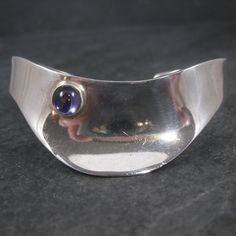 This gorgeous vintage Mexican cuff bracelet is sterling silver. It features a 7mm amethyst gemstone. The face of this bracelet measures 7/8 of an inch and tapers down to 3/8 of an inch. It has an inner circumference of 6 inches, including the 1 inch gap. Weight: 28.4 grams Condition: Excellent Vintage Amethyst Jewelry With Polished Finish, Modern Gemstone Cuff Bracelet For Formal Occasions, Elegant Silver Amethyst Cuff Bracelet, Modern Silver Bangle With Gemstone, Silver Amethyst Gemstone Cuff Bracelet, Modern Silver Gemstone Bangle, Vintage Silver Amethyst Bracelets, Vintage Mexican, Amethyst Gemstone