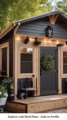 a small wooden shed with lights on the front and side windows, along with potted plants