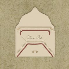 a white envelope with a red ribbon on the front and bottom, sitting against a wallpapered background