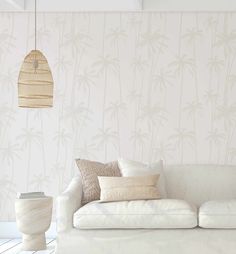 a white couch sitting in front of a wall with palm trees on it's side