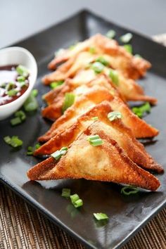 some food is on a black plate and ready to be eaten with dipping sauces