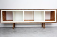 a white and wood shelf with three shelves on each side, in front of a wall