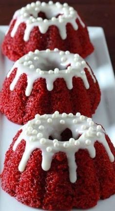 three red velvet bundt cakes with white icing on a square plate, ready to be eaten