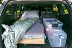 the back end of a car with a bed and two plastic containers