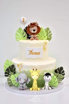 a three tiered cake decorated with animals and leaves