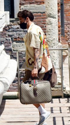 a man with a face mask carrying a suitcase