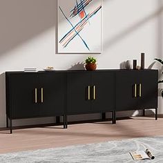 a black cabinet with gold handles in an empty living room, next to a plant