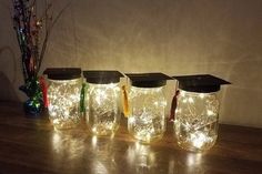 four jars with graduation caps and lights in them are sitting on a table next to a vase