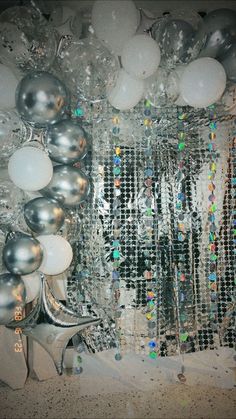 silver and white balloons are hanging on the wall next to a mirror with some disco balls