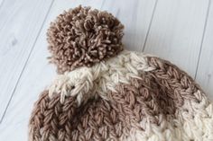 a brown and white knitted hat sitting on top of a wooden floor