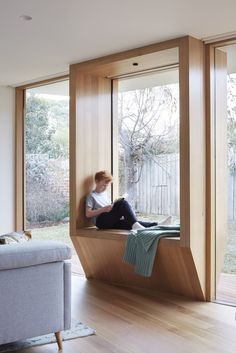 a person sitting on a window sill in a room with wooden floors and walls