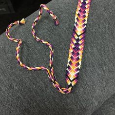 a purple, yellow and pink beaded lanyard on a gray couch with a black background