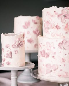 three tiered wedding cakes with pink flowers on them and white frosting, sitting on plates