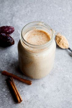 a glass jar filled with liquid next to cinnamon sticks