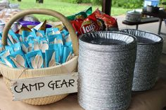 a basket full of camping gear sitting on top of a table next to two tin cans