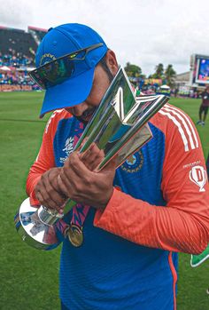 a man holding trophies on top of a field