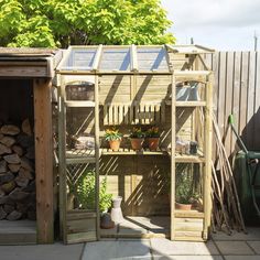 a garden shed with lots of potted plants in the corner and wood stacked on top