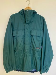 For Sale: PATAGONIA VTG 1994 SST Skanorak Pullover Jacket Green Fly Fishing Hard Shell - L * This Patagonia Skanorak Pullover Jacket is from the Spring 1994 Patagonia Catalog, it is in the Green/Blue color-way. Please see description and ask me any questions you may have! Size: Large ***All Measurements are in INCHES, and were taken with the clothing item laying flat. Shoulder Width: 23 Inches (Shoulder Seam to Shoulder Seam, measured directly across) Chest: 27.5 Inches (Pit to Pit, measured dir Patagonia Casual Windbreaker For Outdoor Activities, Casual Patagonia Windbreaker For Outdoor Activities, Vintage Windbreaker With Adjustable Hood For Outdoor, Long Sleeve Windbreaker With Pockets For Camping, Long Sleeve Windbreaker With Pockets For Adventure, Adventure Windbreaker With Adjustable Hood And Long Sleeve, Long Adventure Parka With Pockets, Long Sleeve Parka With Pockets For Adventure, Patagonia Functional Windbreaker For Outdoor