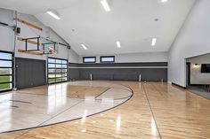 an indoor basketball court with hard wood flooring and glass doors leading to the upper level