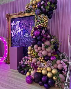 a birthday cake made out of balloons and flowers on top of a purple table cloth