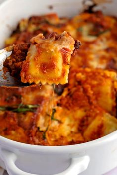 a spoon full of lasagna casserole being lifted from the casserole dish