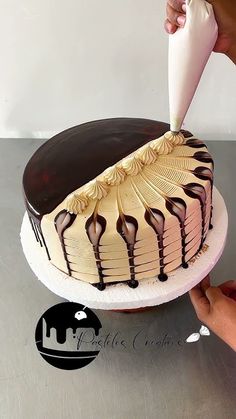 a person is decorating a cake with icing and chocolate on the top layer