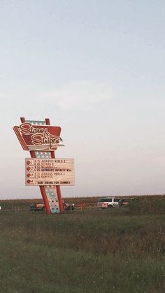 a large sign in the middle of a field with cars parked on the other side