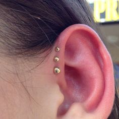 a close up of a person's ear with three small studs on it