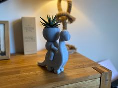 a ceramic planter sitting on top of a wooden table next to a framed photo