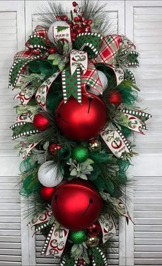 a christmas wreath with red and green ornaments hanging on the side of a white door