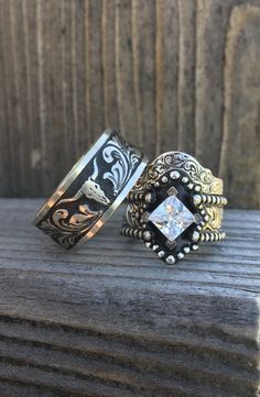 two rings sitting on top of a wooden table next to each other and one has a white diamond in the center