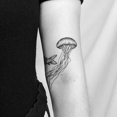 a black and white photo of a woman's arm with a jellyfish tattoo on it