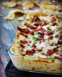 a casserole dish with bacon, cheese and other toppings in a glass dish