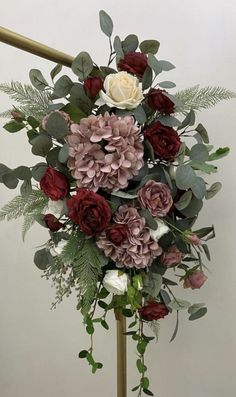 a bouquet of flowers sitting on top of a metal pole in front of a white wall