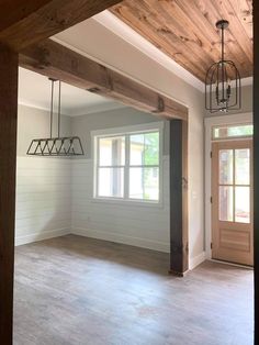 an empty living room with wood beams and light fixtures hanging from the ceiling above it