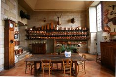 an old fashioned kitchen with many pots and pans on the wall above the table