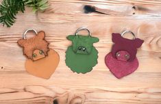 three keychains with different colors and designs on them sitting on a wooden surface