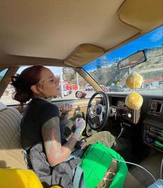 a woman sitting in the driver's seat of a car with tattoos on her arm