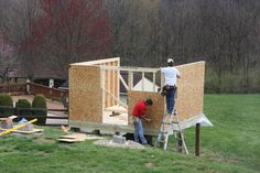 two men are working on the roof of a small house that's being built