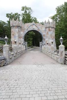 a stone bridge with an archway and gate leading to the entrance into a wooded area