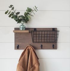 a coat rack with two coats hanging from it's sides and a potted plant next to it