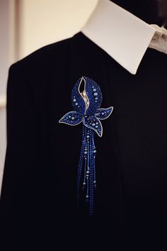 a black shirt with blue beads and a bird brooch