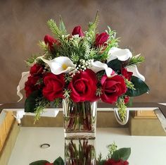 red roses and white calla lilies in a clear vase on a mirrored tray