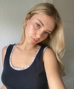 a woman with long blonde hair is posing for the camera while wearing a black tank top